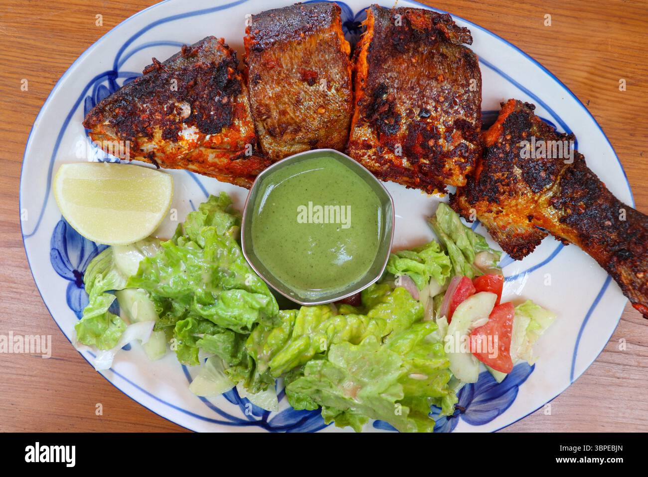 Truite tandoori grillée à la perfection, servie avec chutney vert acidulé, coin de citron et salade verte fraîche. Un plat indien savoureux Banque D'Images