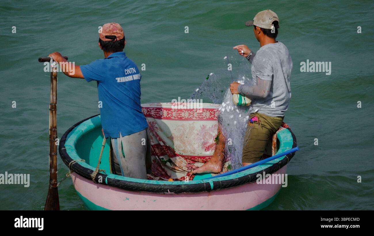 Pêcheurs travaillant à partir d'un panier-bateau vietnamien traditionnel dans les eaux calmes Banque D'Images