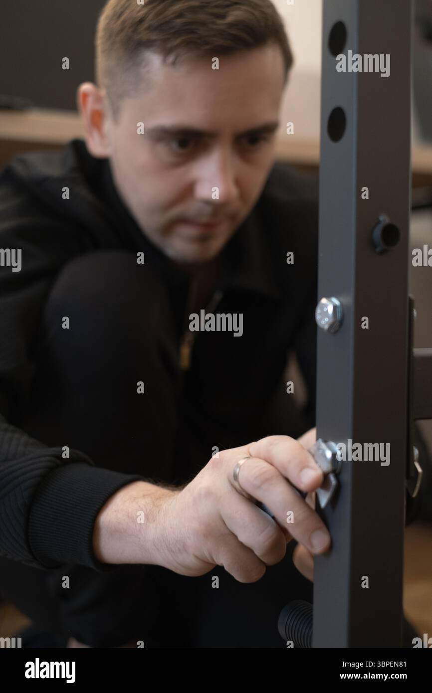 Homme assemblant des meubles dans le salon montrant combien il est facile et pratique de créer du confort avec ses propres mains. Banque D'Images