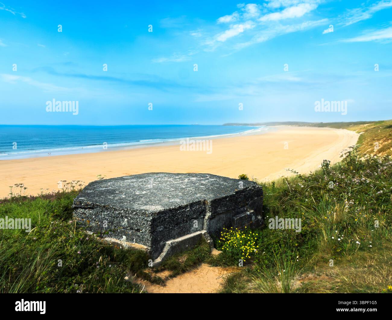 Un bunker en béton, probablement construit par les forces militaires lors d'un conflit passé pour la défense côtière, se trouve sur les dunes herbeuses surplombant une large plage de sable Banque D'Images