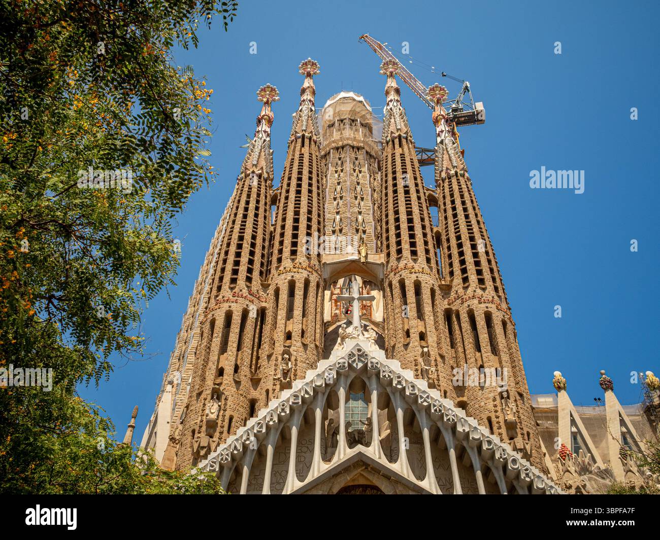 Regardant la façade ornée passion de la Sagrada Familia, avec une grue de construction montrant les travaux en cours, Barcelone, Espagne. Banque D'Images