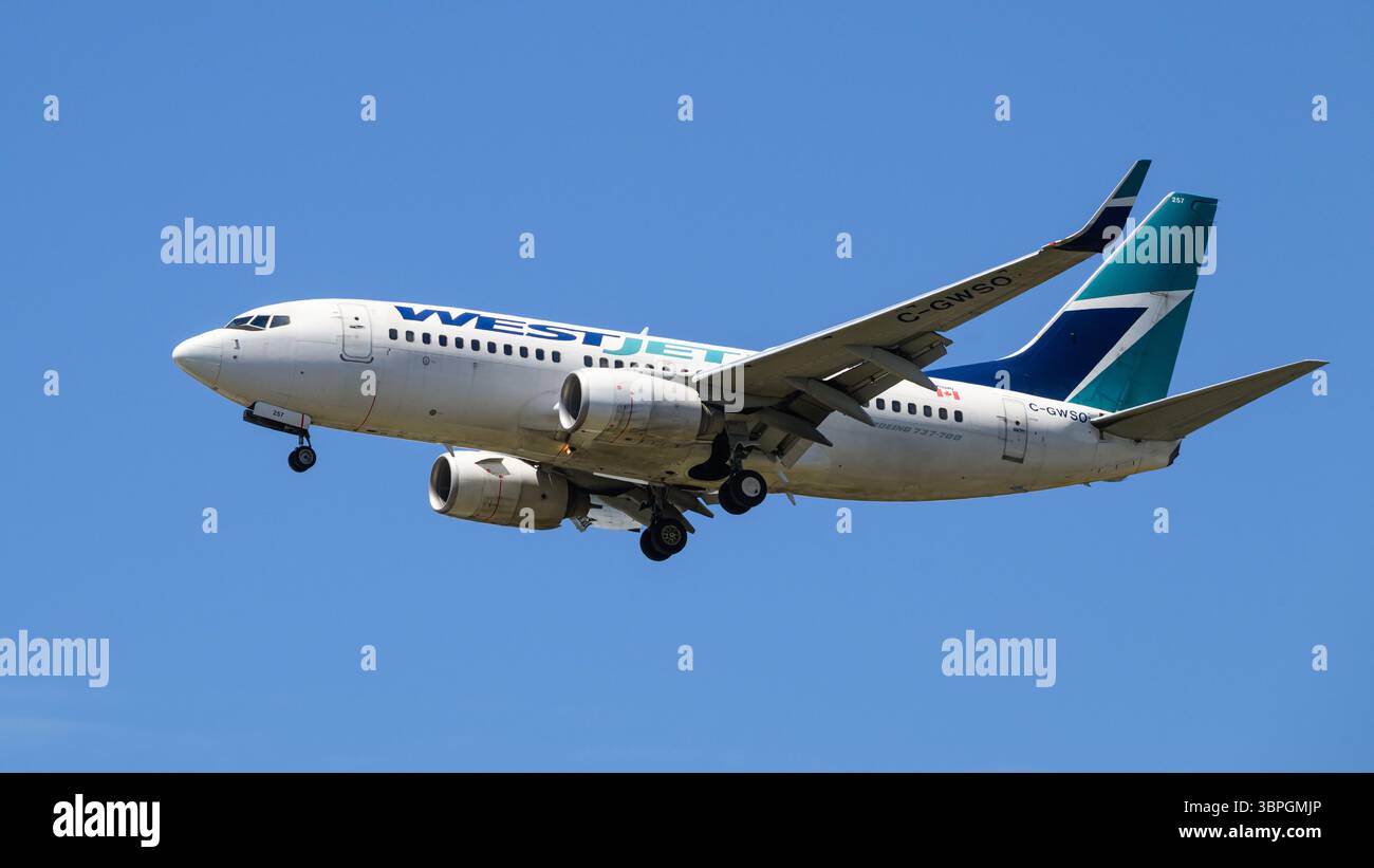 SeaTac, WA, États-Unis - 2 juillet 2025 ; Boeing 737-700 de WestJet dans la livrée de la compagnie atterrissant isolé sur le ciel bleu Banque D'Images