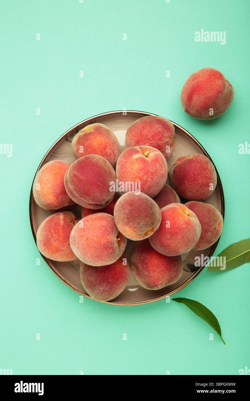 Pêches douces et feuilles sur plaque sombre sur fond de menthe. Vue de dessus Banque D'Images