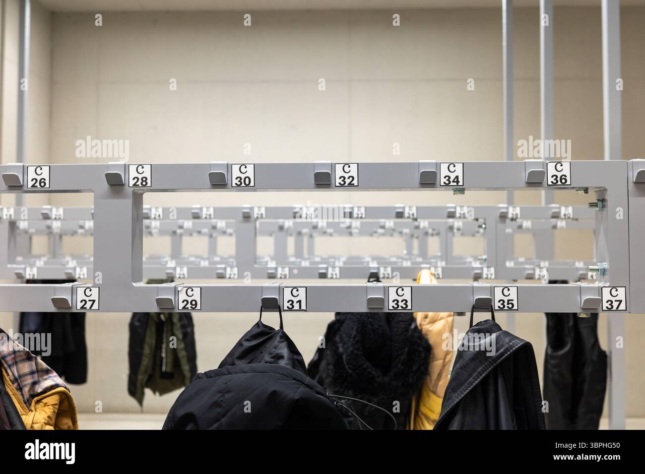 Manteaux et vestes suspendus dans le vestiaire. Photo prise à la lumière artificielle dans un bâtiment d'utilité publique Banque D'Images