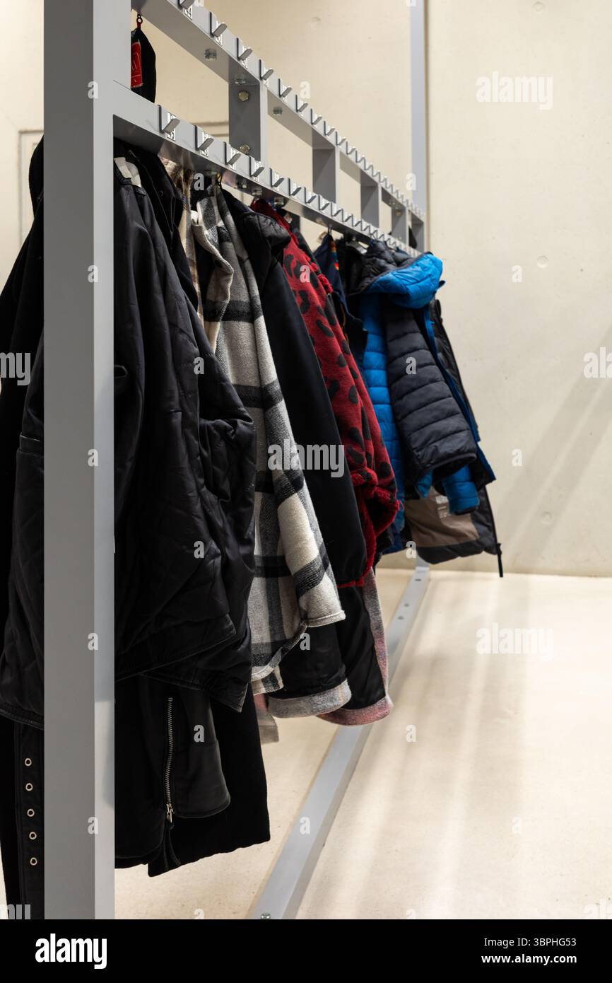 Manteaux et vestes suspendus dans le vestiaire. Photo prise à la lumière artificielle dans un bâtiment d'utilité publique Banque D'Images