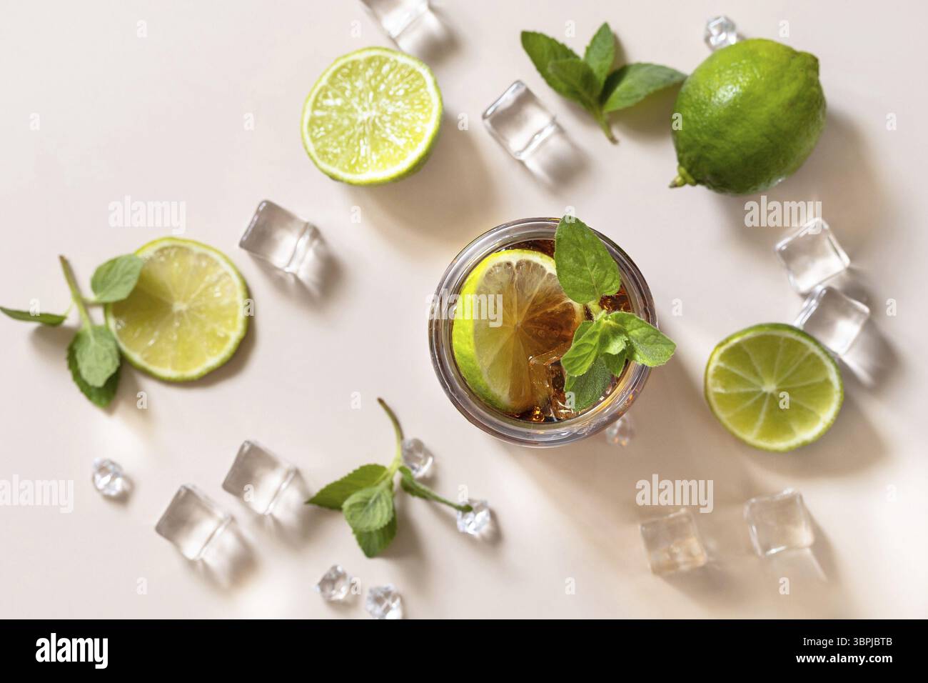 Cuba libre boisson alcoolisée, Cola avec des glaçons ou limonade sur un fond brun pastel. Arrière-plan à plat de la vue de dessus Banque D'Images