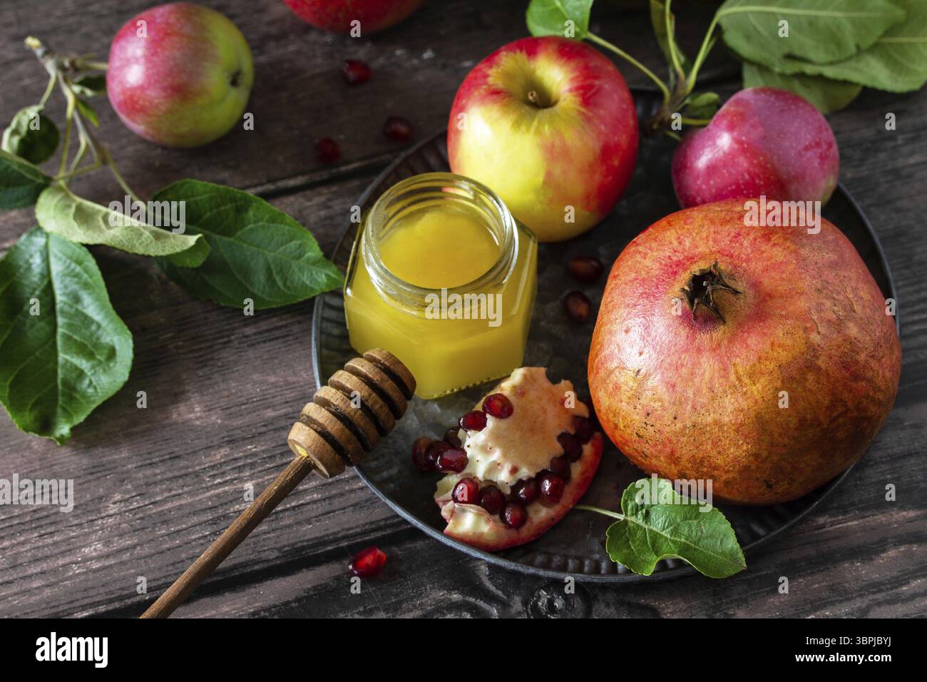 Image religieuse de Rosh hashanah (vacances juives du nouvel an) concept. Symboles traditionnels : miel, pommes et grenade sur une table rustique sombre Banque D'Images