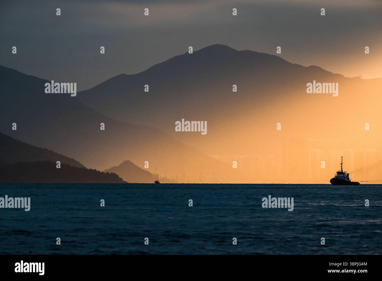 Bel éclairage sur le port, avec des montagnes en arrière-plan, créant un jeu époustouflant de lumière et d'ombre. Banque D'Images