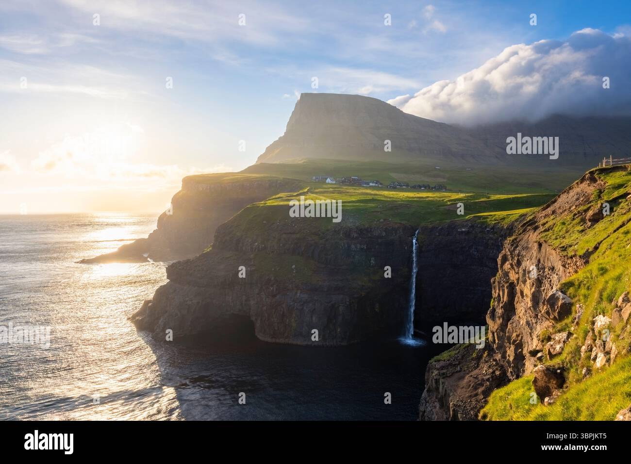 Vue sur la cascade de Mulafossur avec le petit village de Gasadalur. Île de Vagar, Îles Féroé, Danemark, Europe. Banque D'Images