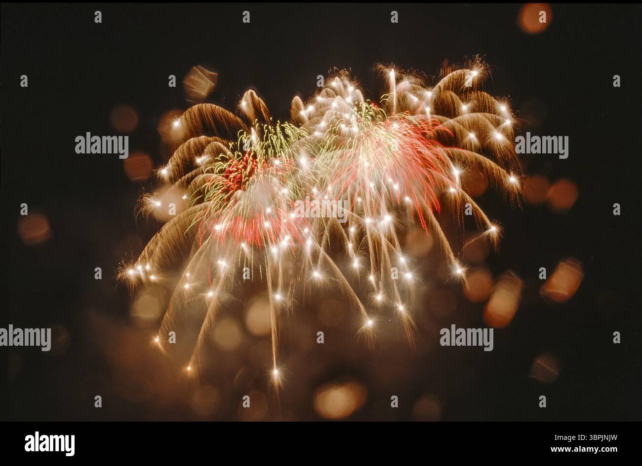Feux d'artifice à haute altitude dans le ciel nocturne sous la pluie avec des taches d'objectif ou des taches d'ouverture causées par des gouttelettes d'eau sur l'objectif Banque D'Images
