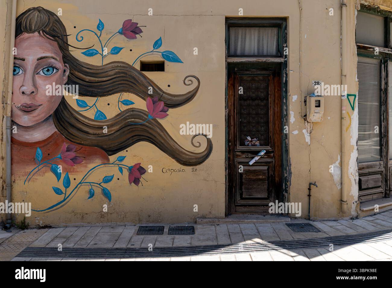 Archanes, Crète, Grèce - 25 juin 2025 : une murale d'une femme aux cheveux coulants améliore un bâtiment à Archanes, Crète. Banque D'Images