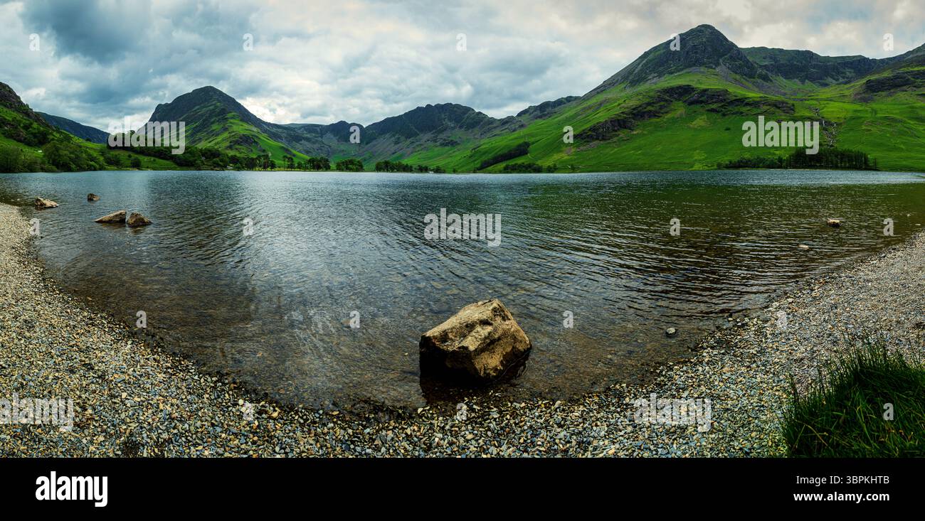 Un paysage panoramique du lac Buttermere par une journée nuageuse d'été, avec une lumière spectaculaire brisant à travers les nuages de pluie, les vagues balayées par le vent sur le lac Banque D'Images