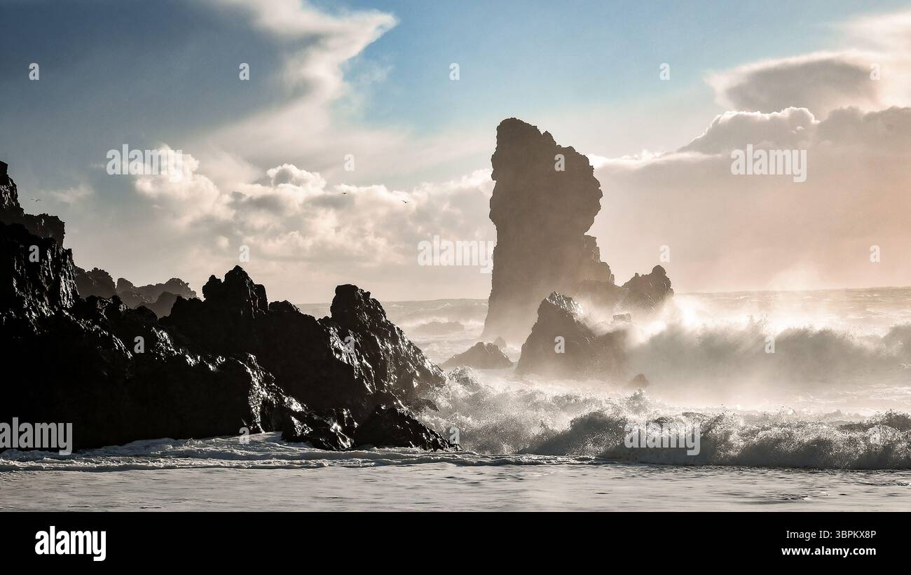Des marées spectaculaires et des vagues qui s'écrasent sous un ciel orageux le long de la plage de sable noir de Reynisfjara, en Islande Banque D'Images