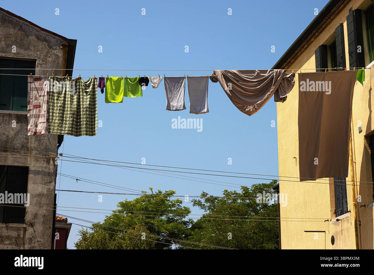 Séchage coloré du linge sur les lignes de tissu de manière italienne traditionnelle. Des cordes tendues entre de vieux bâtiments sous un ciel bleu clair par une journée ensoleillée à Mura Banque D'Images
