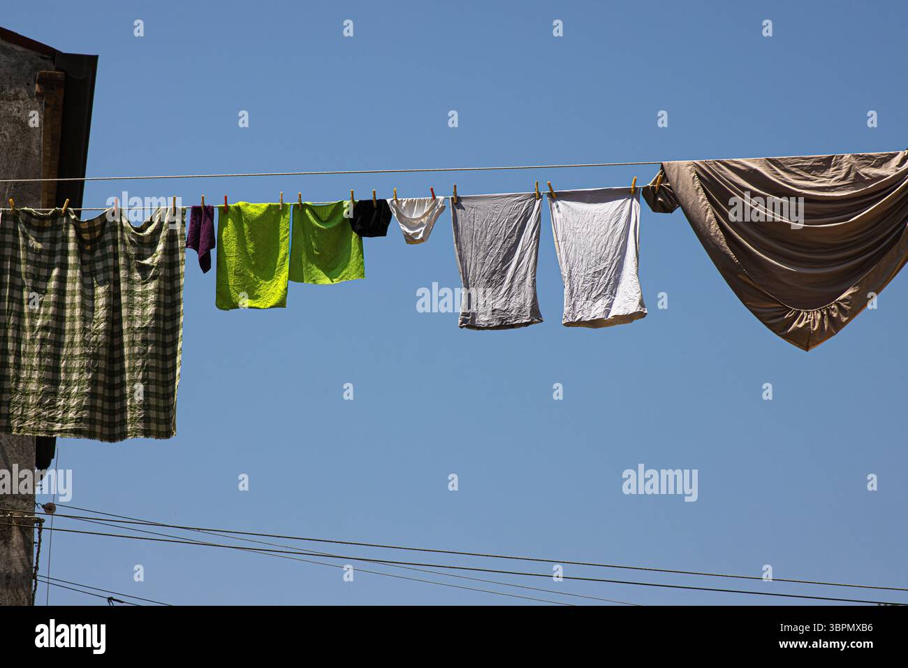 Séchage coloré du linge sur les lignes de tissu de manière italienne traditionnelle. Des cordes tendues entre de vieux bâtiments sous un ciel bleu clair par une journée ensoleillée à Mura Banque D'Images