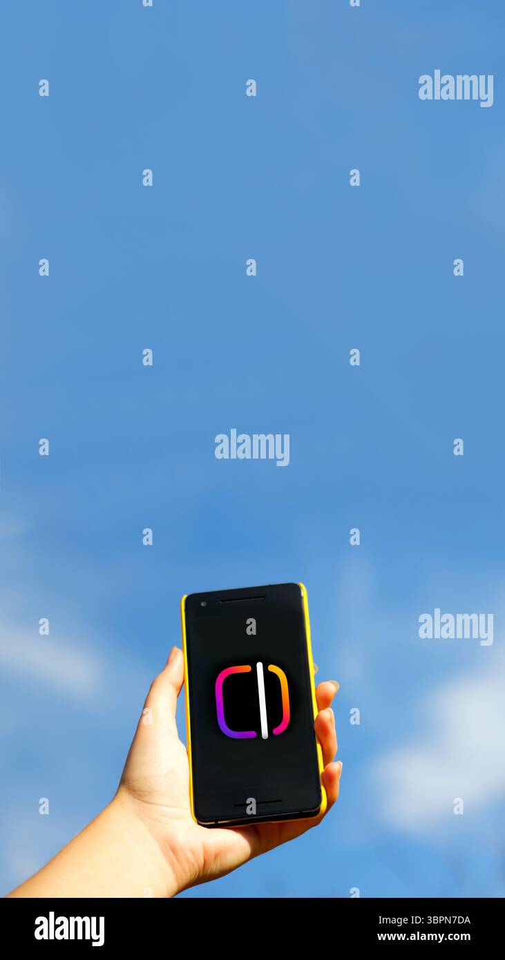 Une main tenant un smartphone affichant une interface bleue d'application de médias sociaux, activement engagée dans la création vidéo et les modifications pour Instagram Reels ou une histoire Banque D'Images