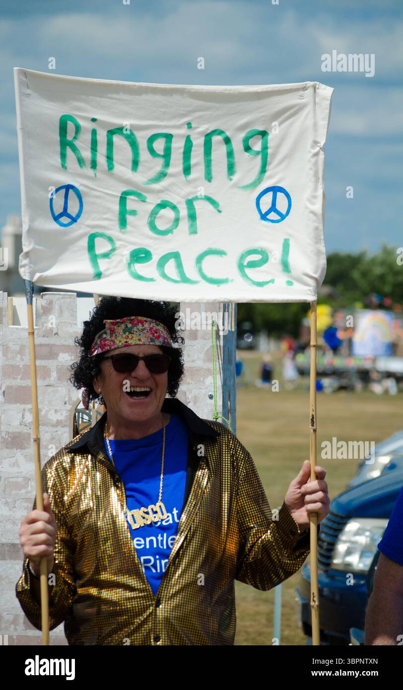 un homme déguisé en hippie tenant une bannière disant que la paix sonnera pour la paix dans les lettles verts essex uk Banque D'Images