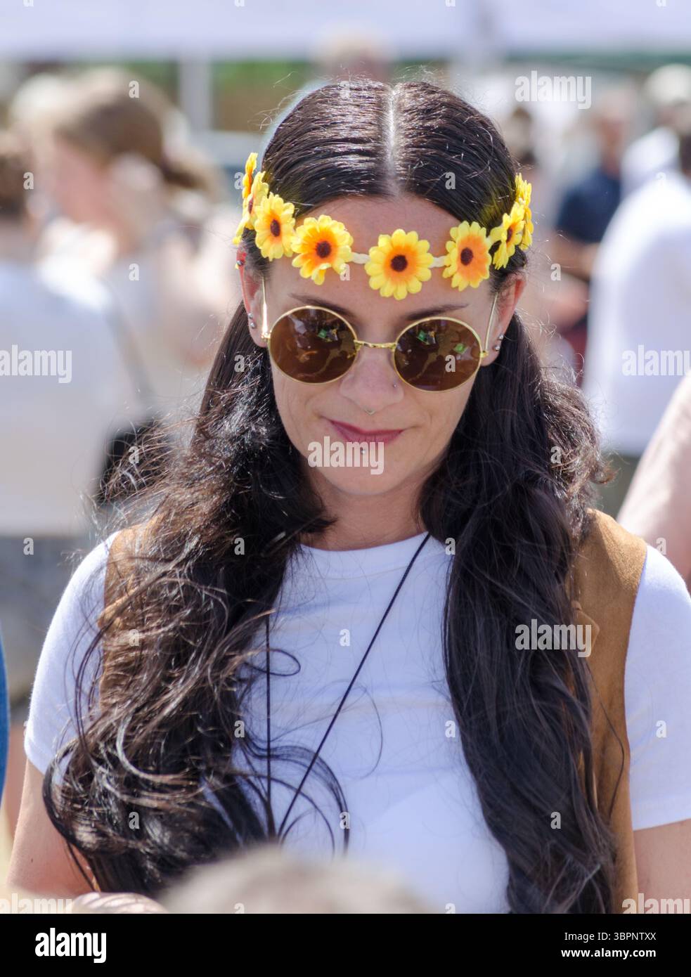 Une femme avec de longs cheveux bruns regardant vers le bas habillée comme hippy au village fete Great bently essex uk Banque D'Images