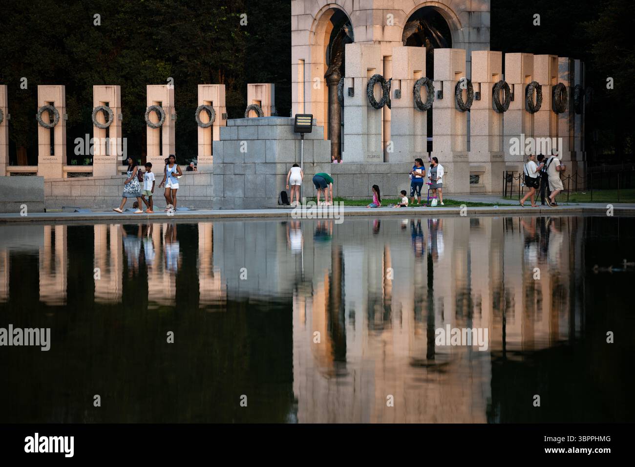 WASHINGTON DC — le Mémorial national de la seconde Guerre mondiale se reflète dans les eaux calmes du bassin réfléchissant du National Mall. Le mémorial, inauguré en 2004, rend hommage aux 16 millions d'Américains qui ont servi dans les forces armées pendant la seconde Guerre mondiale et aux plus de 400 000 morts dans le conflit. Le mémorial comprend 56 piliers de granit représentant les états et territoires américains, disposés autour d'une place centrale avec des fontaines. Situé entre le Lincoln Memorial et le Washington Monument, le mémorial se trouve à l'extrémité ouest du Reflecting Pool, qui a été construit à l'origine en 1922 dans le cadre de l'église Banque D'Images