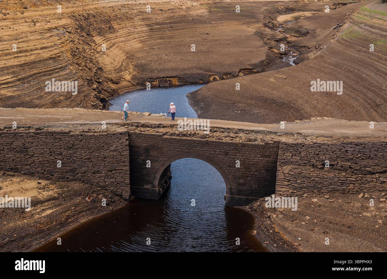 Les gens marchent sur un pont qui est normalement submergé par Baitings Reservoir à Ripponden, West Yorkshire. Les ménages du Yorkshire sont devenus les premiers à être frappés par une interdiction de canalisations par Yorkshire Water, après des mois de temps extrêmement chaud et sec à travers l'Angleterre. Date de la photo : mercredi 9 juillet 2025. Banque D'Images