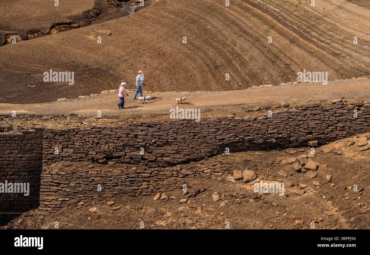 Les gens marchent le long d'un chemin qui est normalement submergé par Baitings Reservoir à Ripponden, West Yorkshire. Les ménages du Yorkshire sont devenus les premiers à être frappés par une interdiction de canalisations par Yorkshire Water, après des mois de temps extrêmement chaud et sec à travers l'Angleterre. Date de la photo : mercredi 9 juillet 2025. Banque D'Images