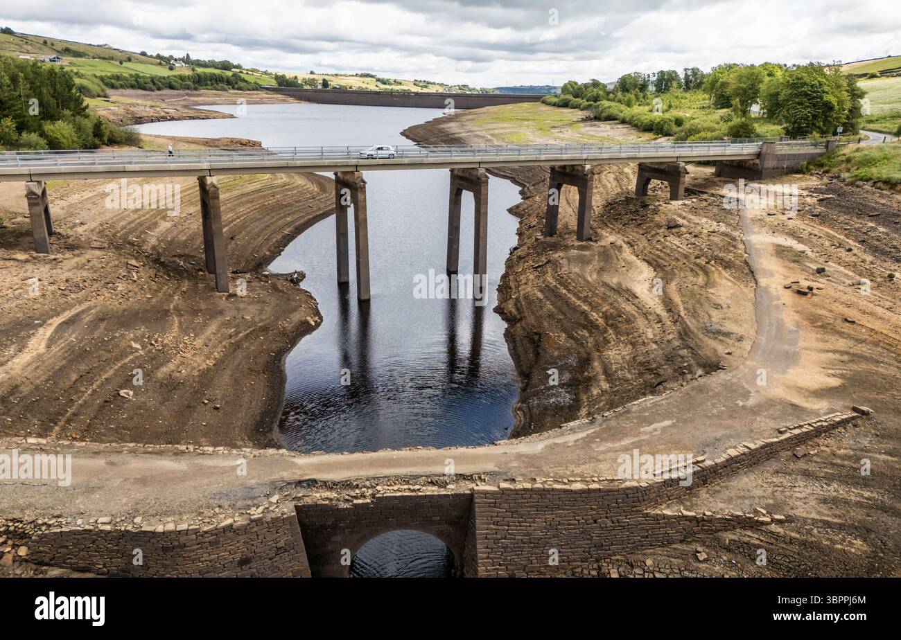 Terre fissurée sèche au réservoir Baitings à Ripponden, West Yorkshire. Les ménages du Yorkshire sont devenus les premiers à être frappés par une interdiction de canalisations par Yorkshire Water, après des mois de temps extrêmement chaud et sec à travers l'Angleterre. Date de la photo : mercredi 9 juillet 2025. Banque D'Images