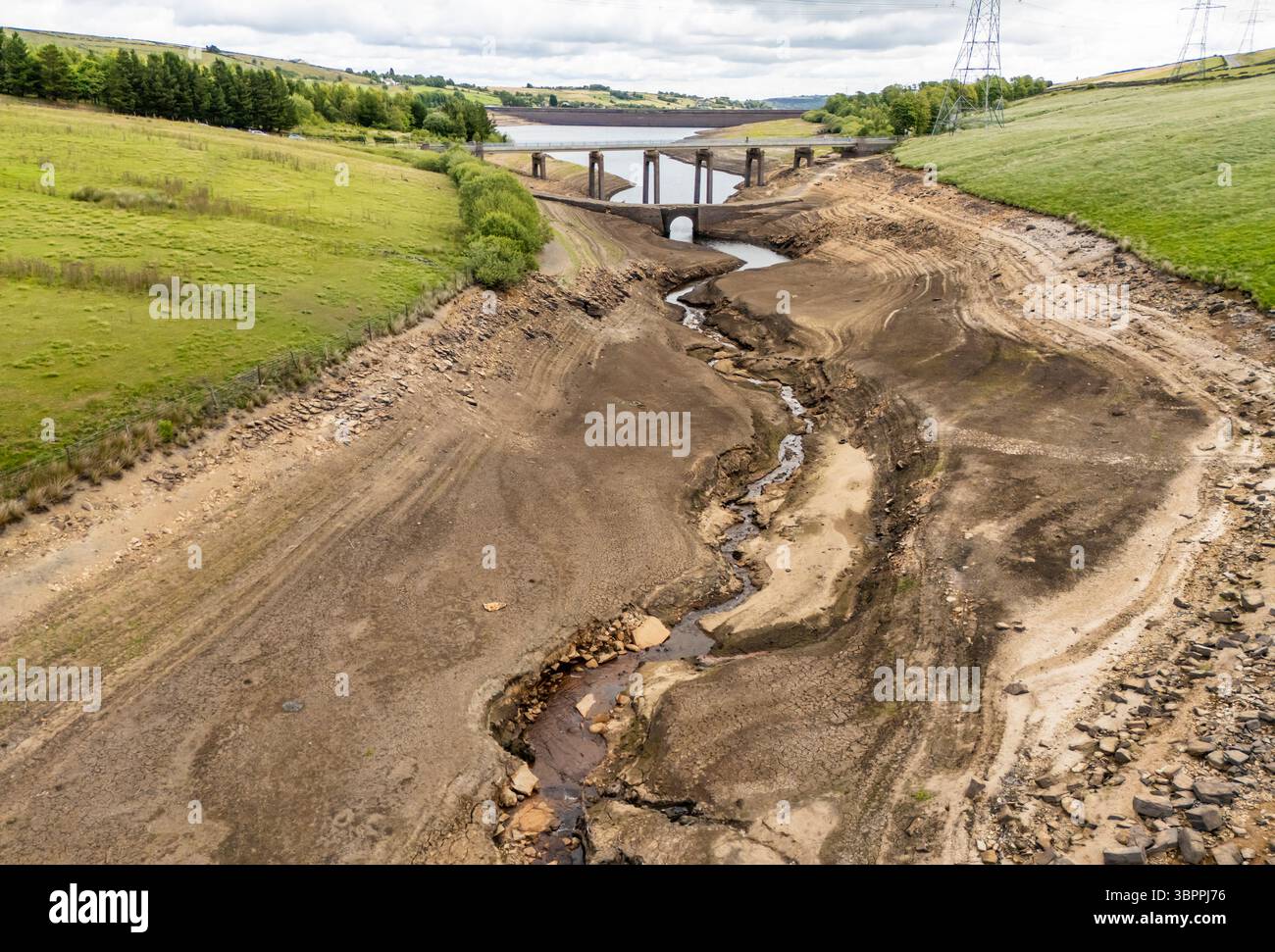 Terre fissurée sèche au réservoir Baitings à Ripponden, West Yorkshire. Les ménages du Yorkshire sont devenus les premiers à être frappés par une interdiction de canalisations par Yorkshire Water, après des mois de temps extrêmement chaud et sec à travers l'Angleterre. Date de la photo : mercredi 9 juillet 2025. Banque D'Images