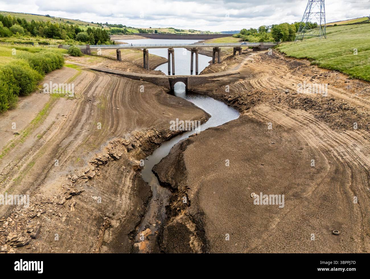 Terre fissurée sèche au réservoir Baitings à Ripponden, West Yorkshire. Les ménages du Yorkshire sont devenus les premiers à être frappés par une interdiction de canalisations par Yorkshire Water, après des mois de temps extrêmement chaud et sec à travers l'Angleterre. Date de la photo : mercredi 9 juillet 2025. Banque D'Images