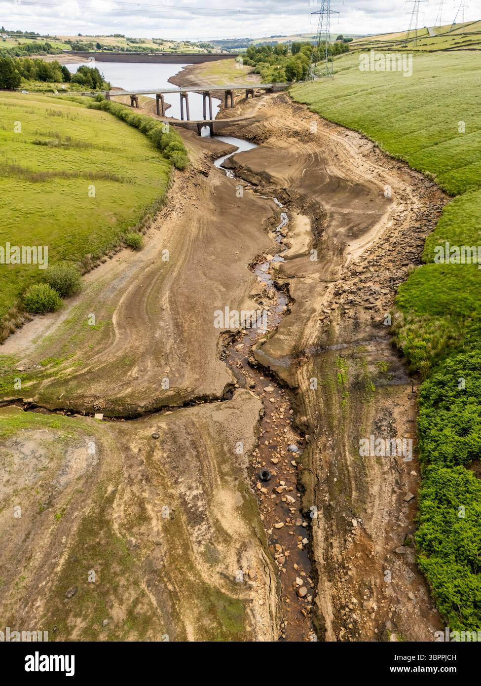 Terre fissurée sèche au réservoir Baitings à Ripponden, West Yorkshire. Les ménages du Yorkshire sont devenus les premiers à être frappés par une interdiction de canalisations par Yorkshire Water, après des mois de temps extrêmement chaud et sec à travers l'Angleterre. Date de la photo : mercredi 9 juillet 2025. Banque D'Images