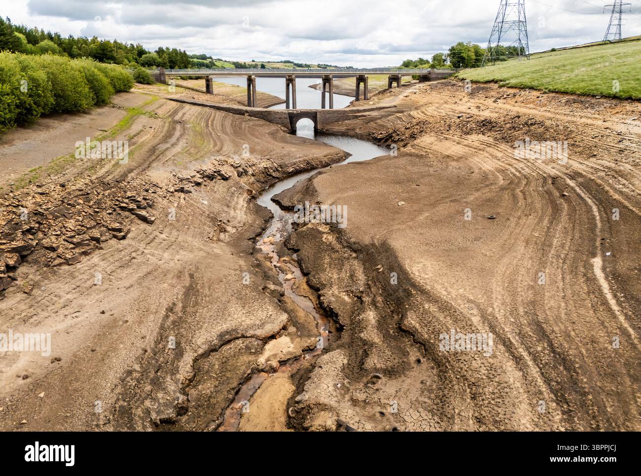 Terre fissurée sèche au réservoir Baitings à Ripponden, West Yorkshire. Les ménages du Yorkshire sont devenus les premiers à être frappés par une interdiction de canalisations par Yorkshire Water, après des mois de temps extrêmement chaud et sec à travers l'Angleterre. Date de la photo : mercredi 9 juillet 2025. Banque D'Images
