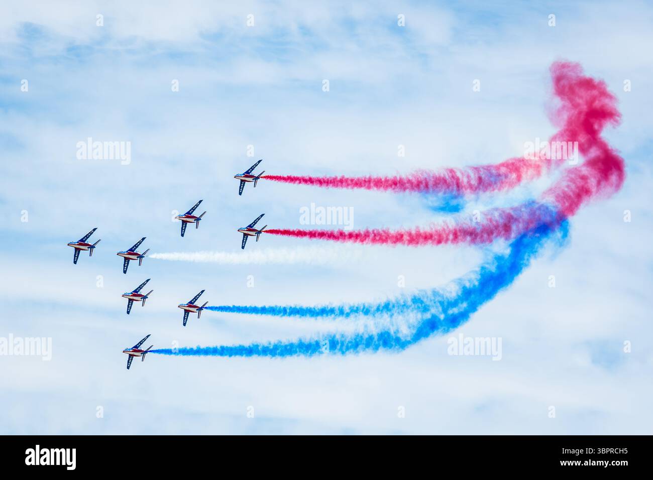 Les huit AlphaJets de la patrouille de France volent en formation Concorde avec de la fumée bleue, blanche et rouge lors d'une exposition aérienne. Banque D'Images