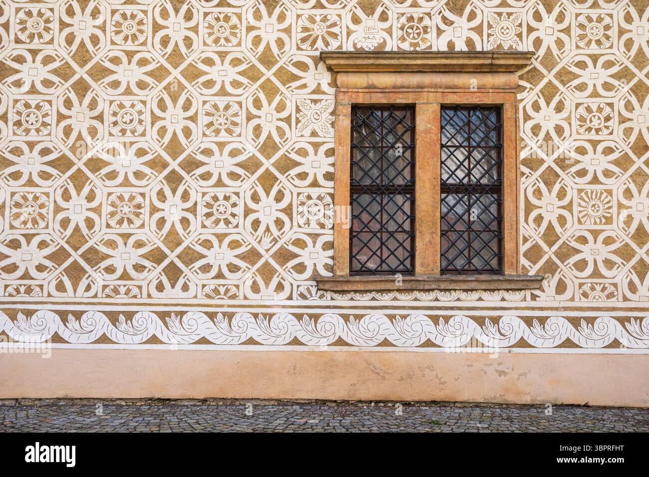 Ancienne fenêtre avec caillebotis en métal décorant une façade de sgraffito en République tchèque Banque D'Images