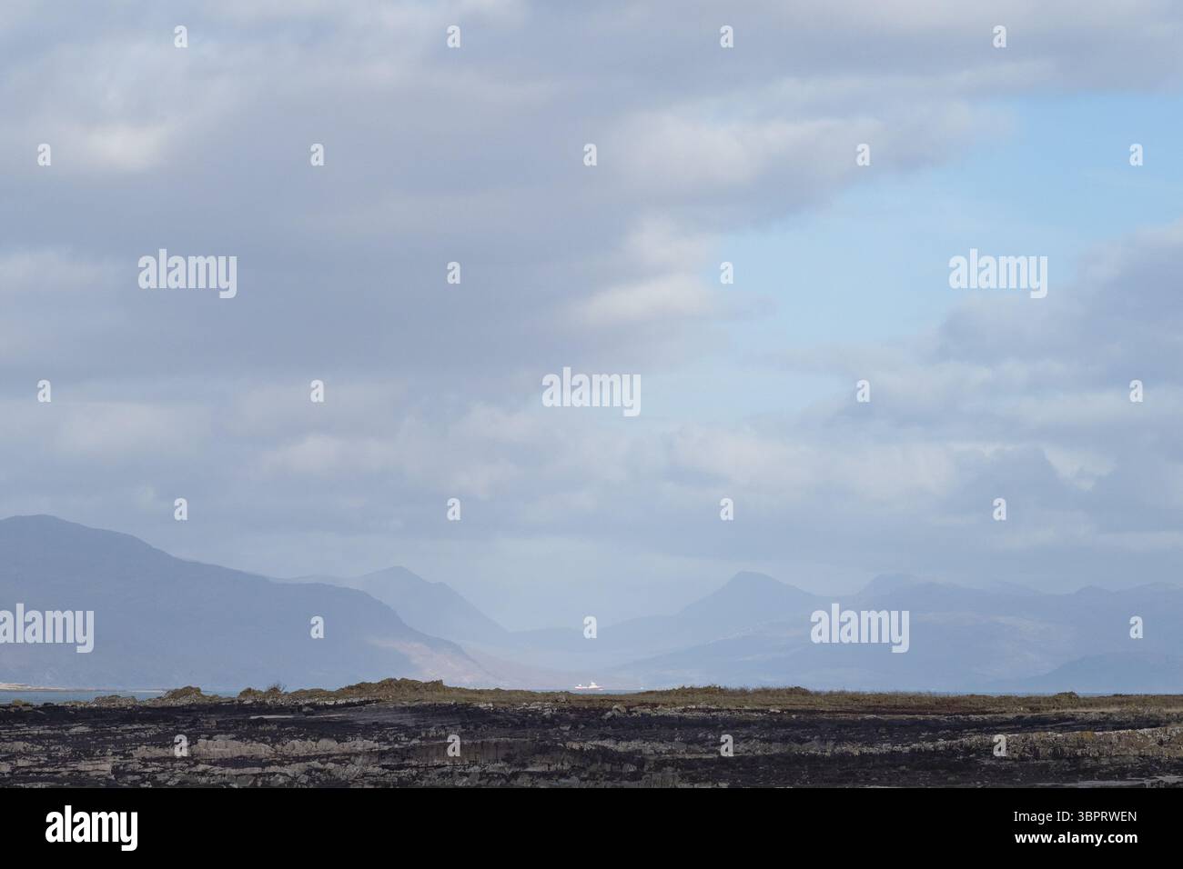 Vue depuis Harrapool, île de Skye, Écosse, à travers Broadford Bay jusqu'aux collines et à un petit navire luttant dans l'eau agitée. Nuages et puits de lumière du soleil. Banque D'Images