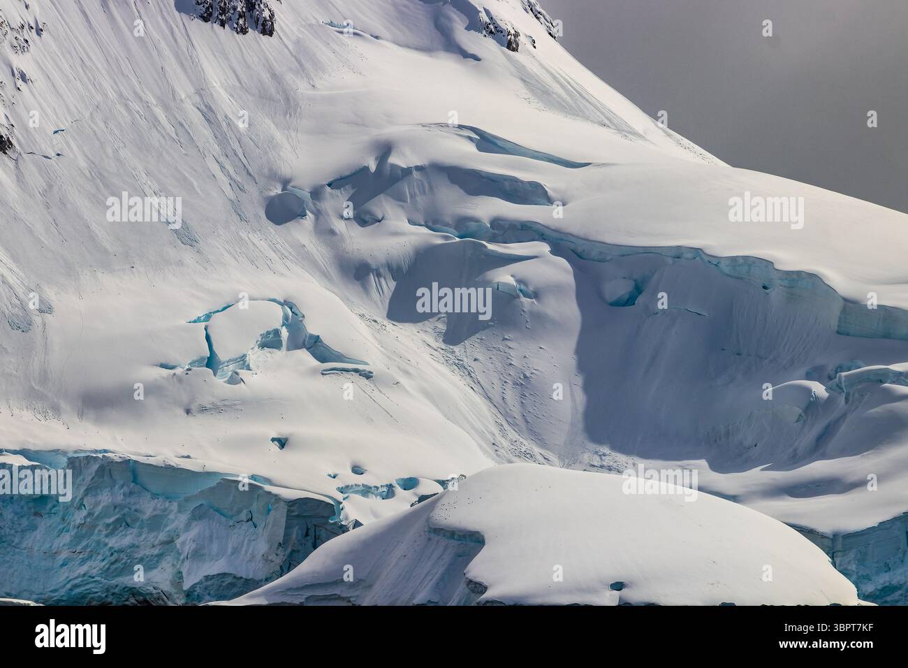 Vue du littoral de la péninsule antarctique du côté de l'océan. Montagnes avec neige et glace, sous une épaisse couche de nuages. Banque D'Images