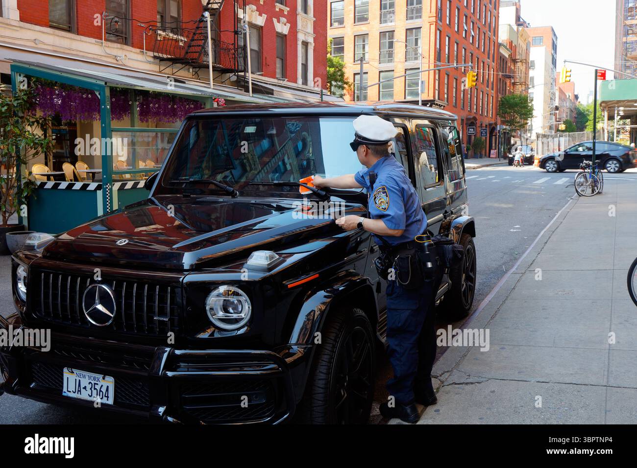 Un flic de la circulation de New York émettant un ticket de stationnement pour une voiture stationnée illégalement à New York. Banque D'Images