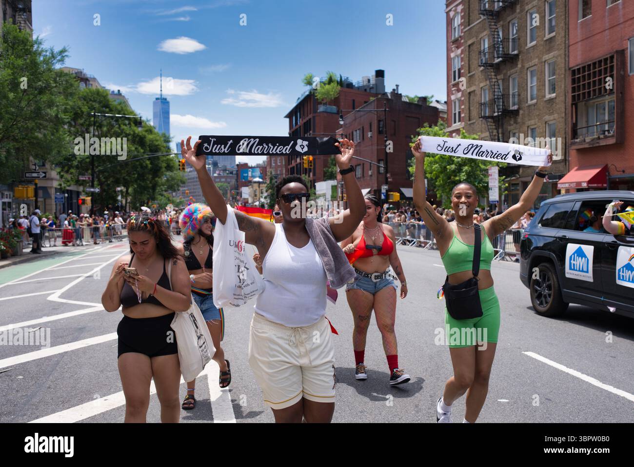 Un groupe de femmes, certaines nouvellement mariées, célèbrent lors d'un défilé de la fierté. Ils tiennent des bannières 'Just Married' et sont entourés par d'autres spectateurs. Le se Banque D'Images