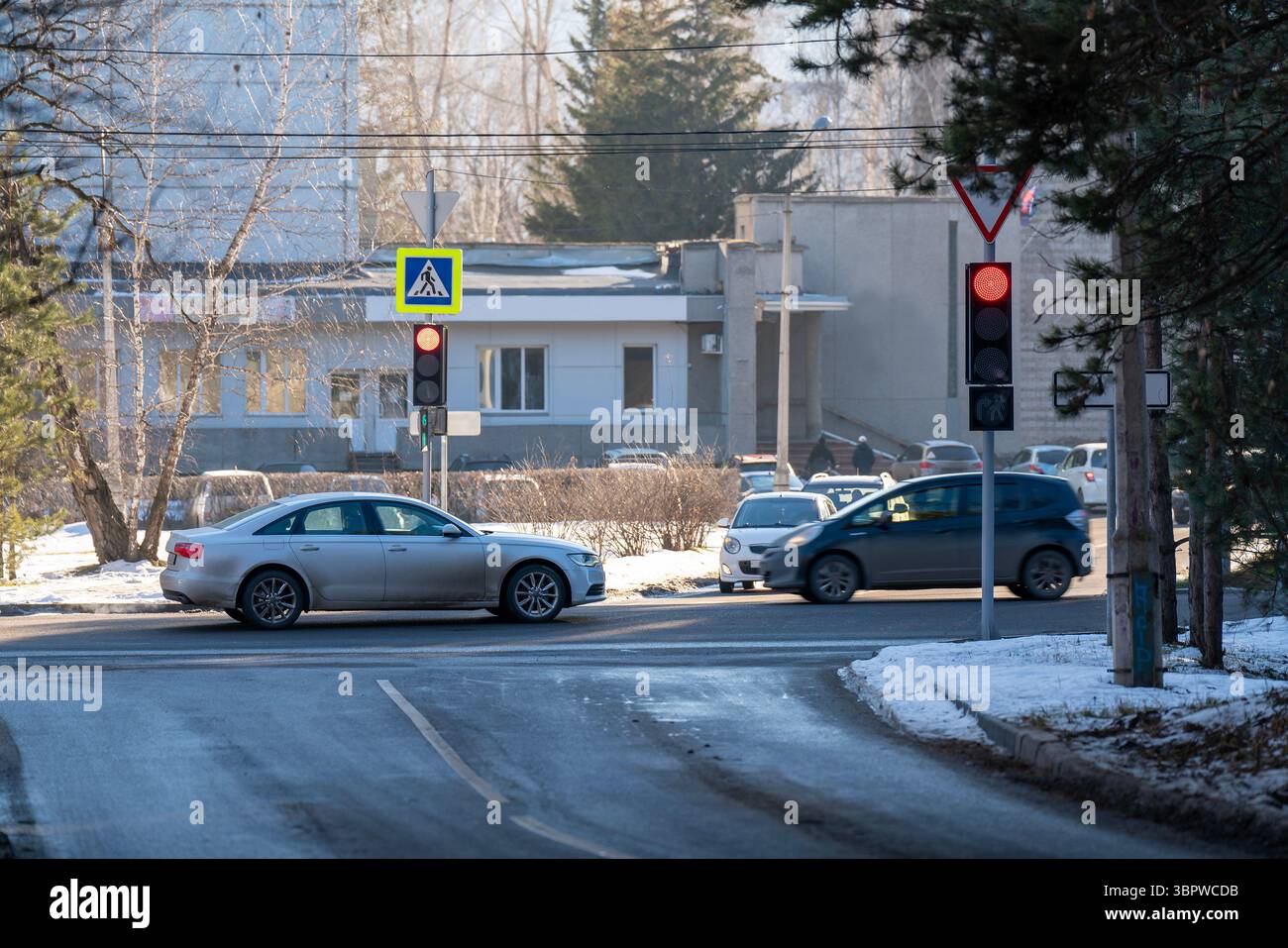 Intersection hivernale avec des voitures en mouvement dans les banlieues. Feu rouge. Banque D'Images
