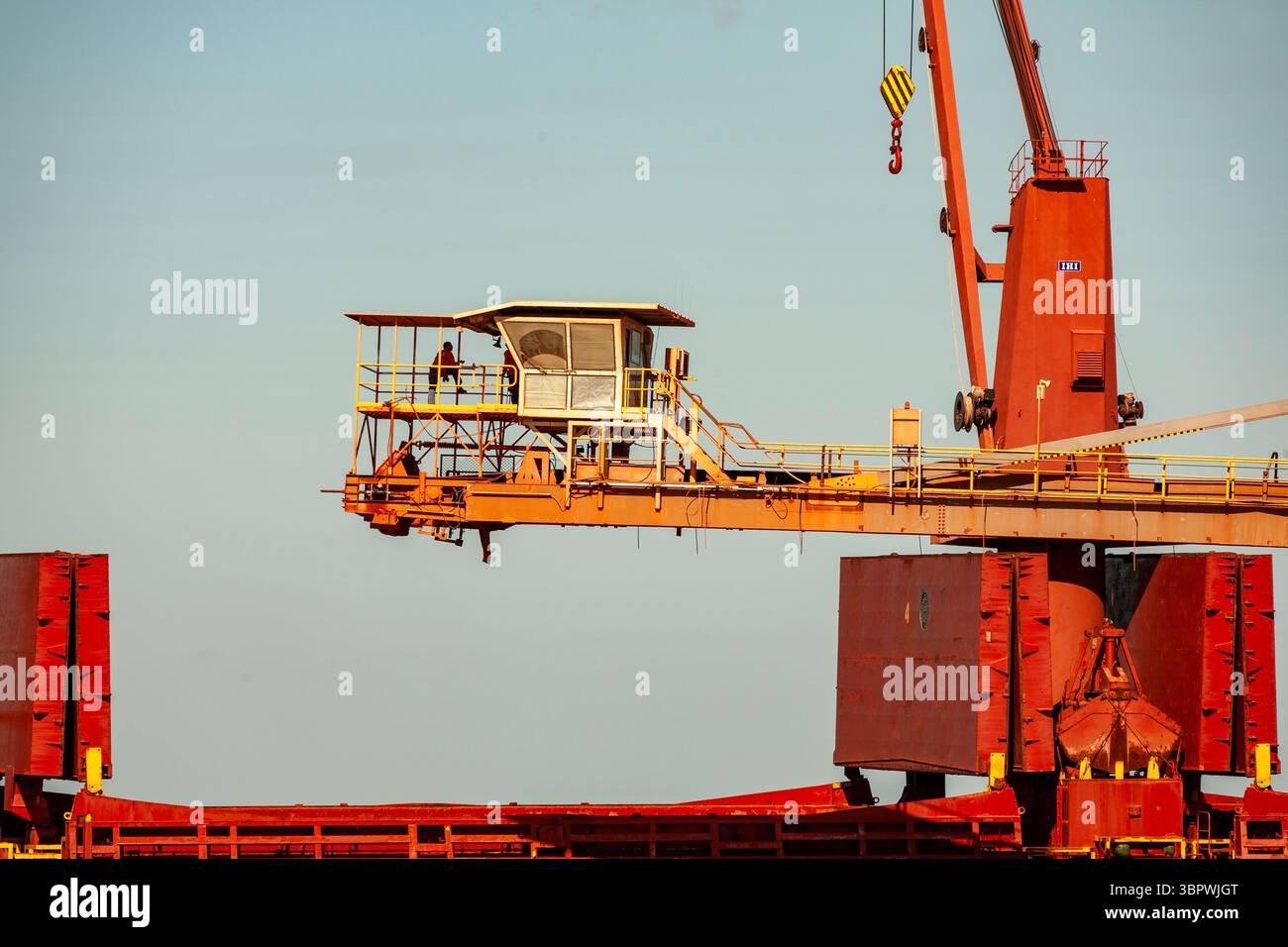 un homme debout sur un pont de convoyeur ferroviaire chargement de bauxite coque de navire rio tinto lorim point terminal emerald navire a amarré un système de convoyeur surélevé Banque D'Images
