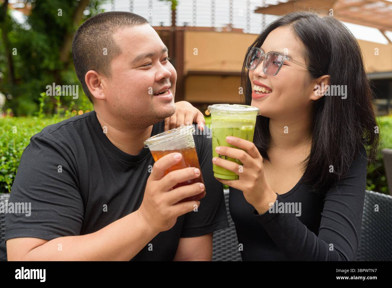 Heureux couple asiatique assis ensemble dans le restaurant de café en plein air pendant l'été Banque D'Images
