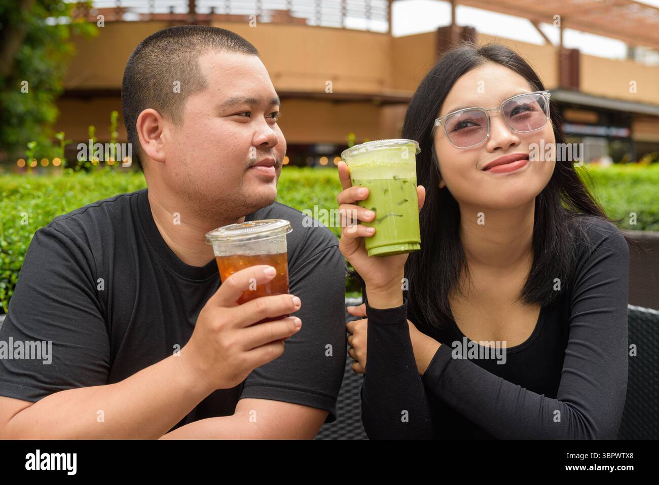 Heureux couple asiatique assis ensemble dans le restaurant de café en plein air pendant l'été Banque D'Images