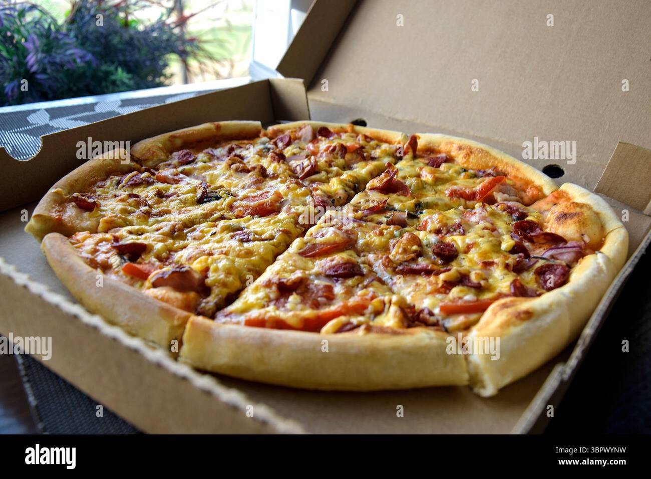 Délicieux ​​pizza tranchés avec saucisse et fromage dans un emballage en carton. Gros plan. Banque D'Images