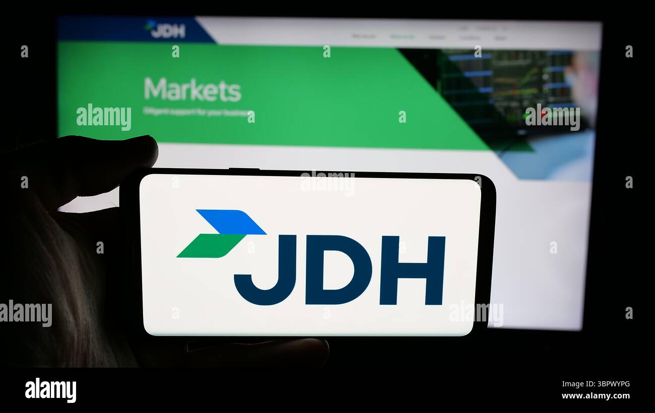 Stuttgart, Allemagne - 05-07-2025 : personne tenant un téléphone portable avec le logo de la société américaine J.D. Heiskell Holdings LLC (JDH) sur l'écran devant la page Web. Banque D'Images