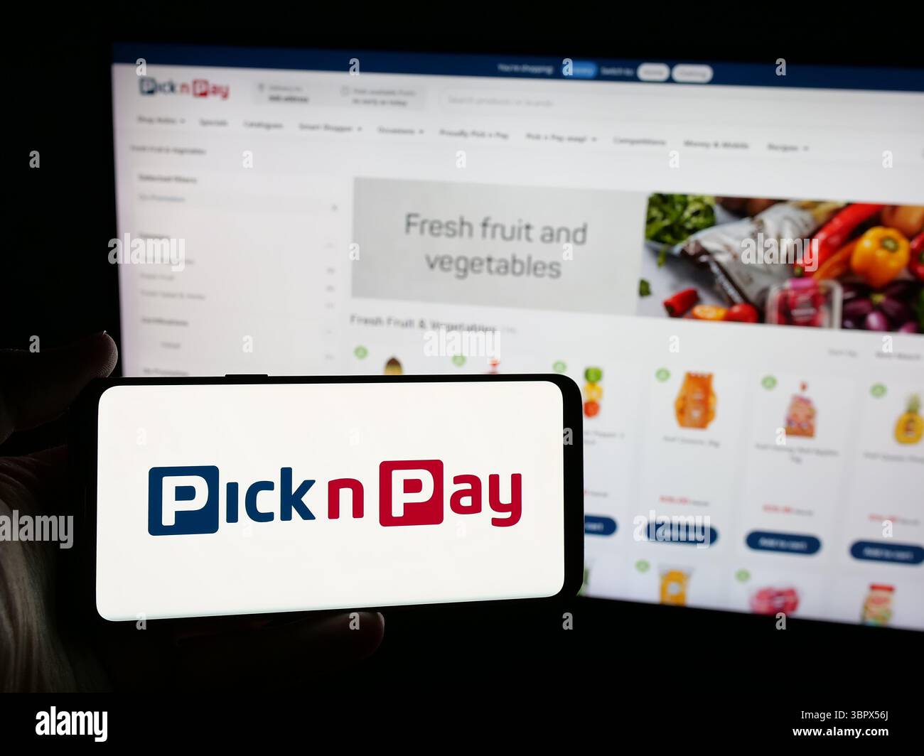 Stuttgart, Allemagne - 2025-05-05 : personne tenant un smartphone avec le logo de l'entreprise de vente au détail d'épicerie Pick n Pay Group Ltd sur l'écran devant le site Web. Banque D'Images
