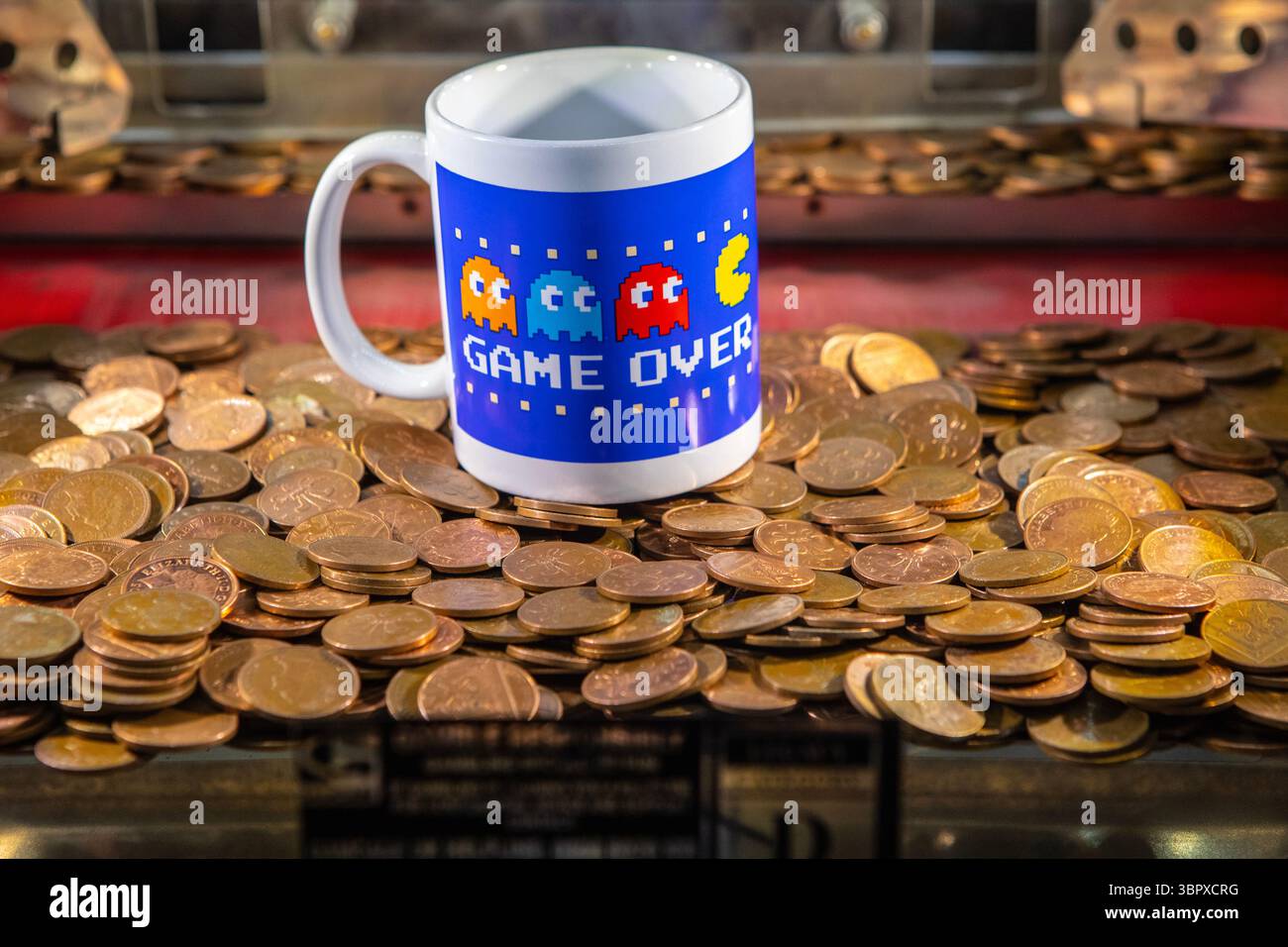 Une tasse PAC Man photographiée à l'intérieur d'une machine à pièces dans une arcade de divertissement. Banque D'Images