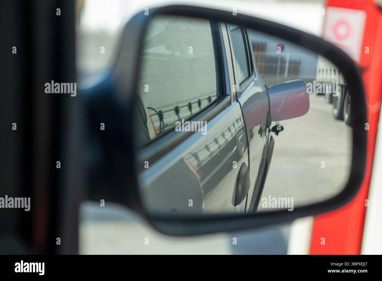 Le rétroviseur d'une voiture montre un panneau rouge et blanc. Le panneau est sur le côté d'un bâtiment Banque D'Images