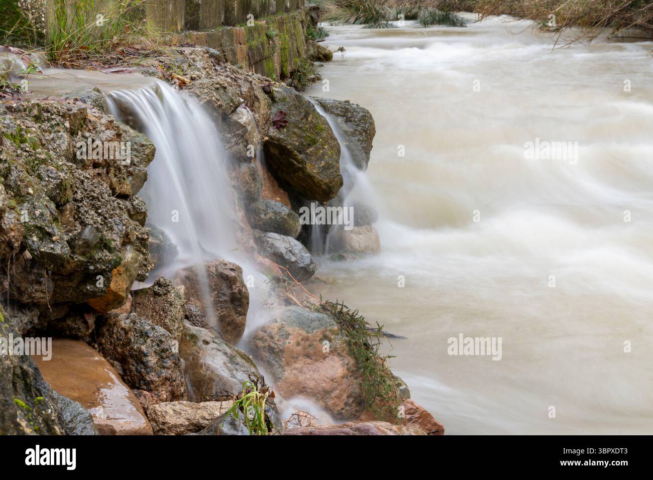 Une rivière avec une cascade et des rochers en arrière-plan. L'eau coule et les rochers sont dispersés autour de la rivière Banque D'Images