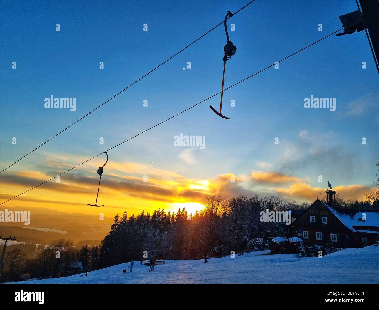 Les télésièges vides sont dessinés contre un ciel coloré et sombre au crépuscule, marquant la fin tranquille d'une journée d'hiver dans une station de montagne. - Image de stock capturée avec un smartphone