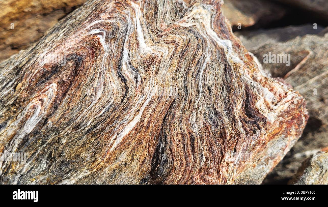 Gros plan d'un morceau de pierre multicouches unique avec des structures de couleurs naturelles ressemblant à des vagues Banque D'Images