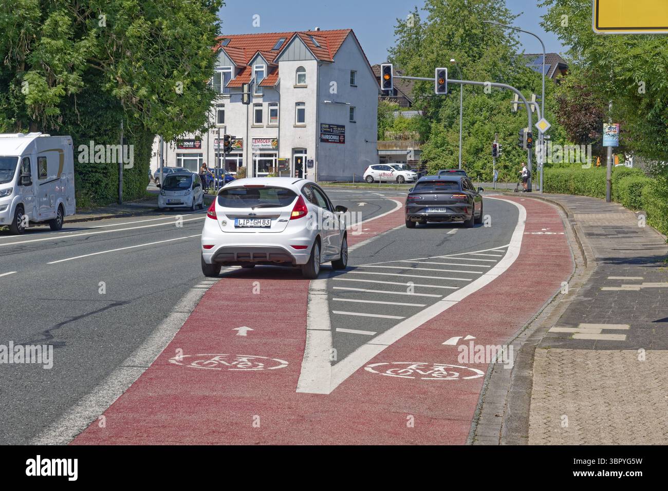 Voies cyclables divisées pour les cyclistes qui vont tout droit et qui tournent à droite devant un feu de circulation sur Herforder Strasse. La voie de virage à droite pour la moto Banque D'Images