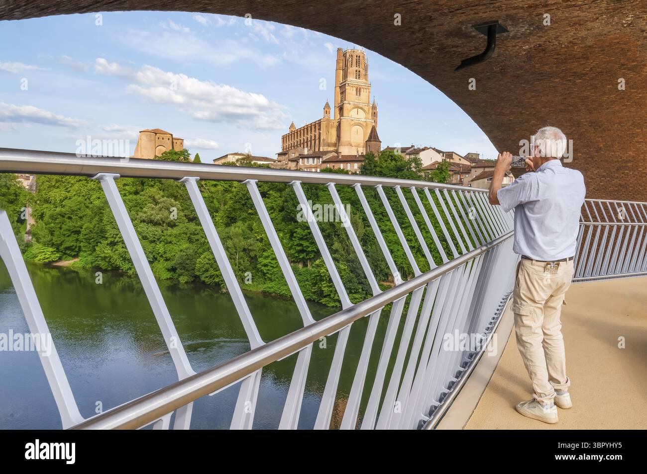 Homme photographiant avec son téléphone portable sur la nouvelle passerelle d'Albi de 200 mètres de long, conçue par Marc Mimram, debout au-dessus de la rivière Tarn et Overlookin Banque D'Images
